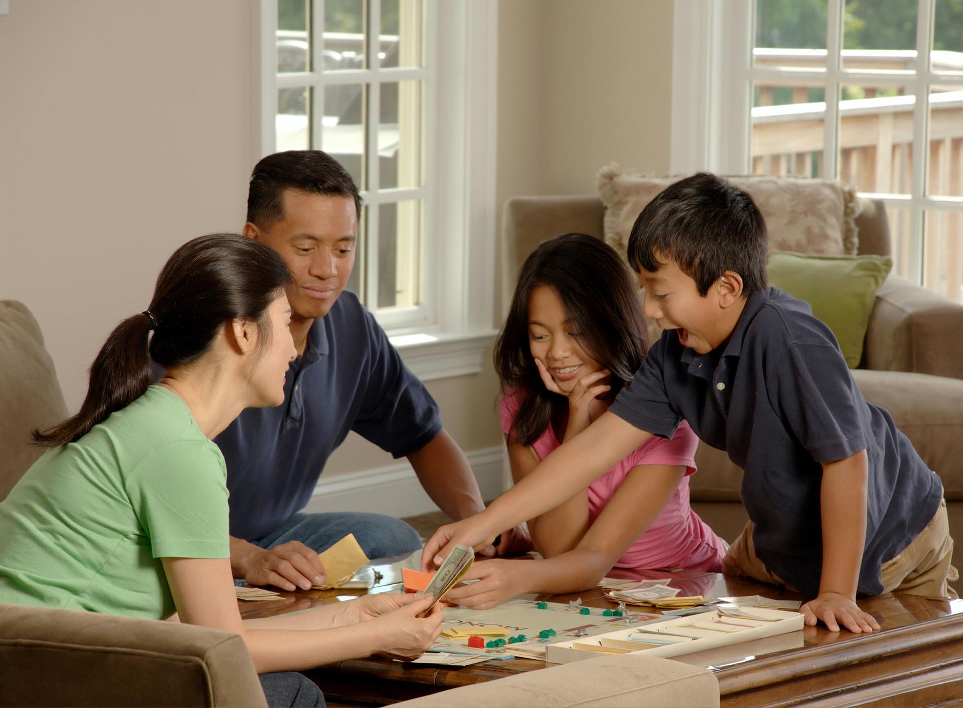 An Asian Family Sitting Around A Coffee Table Playing A Board Game