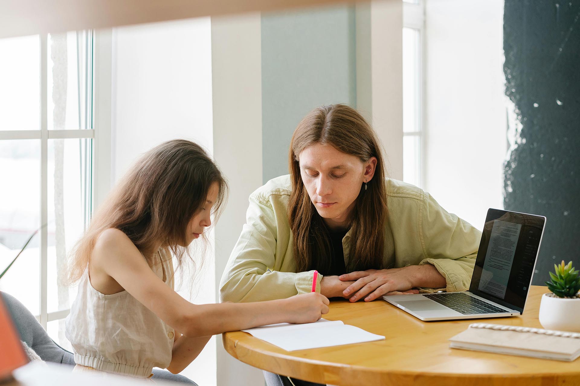 Female Student Writing Task With Male Tutor During Study Session In Australia